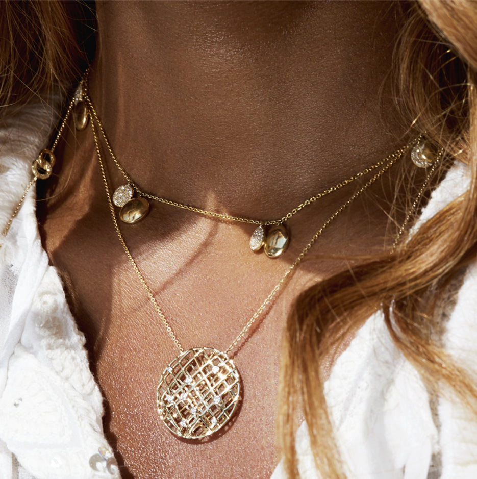 Close up of woman's neck adorned with Luvente necklaces in gold