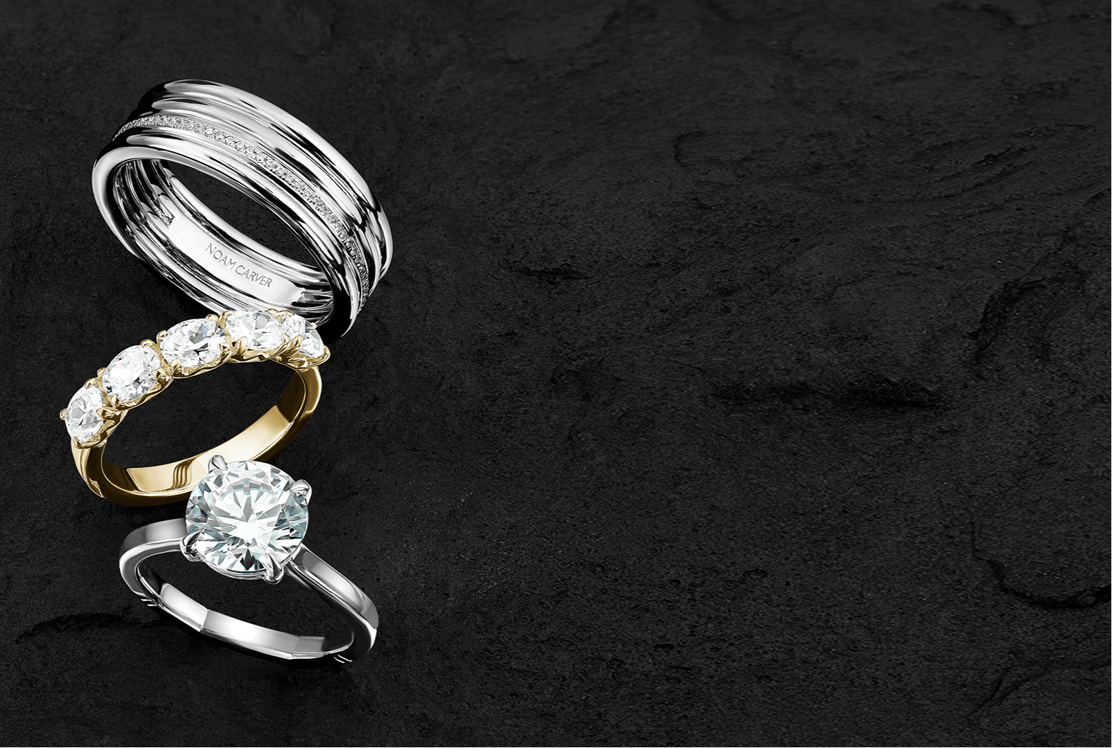 Stack of three Noam Carver rings on a dark grey background