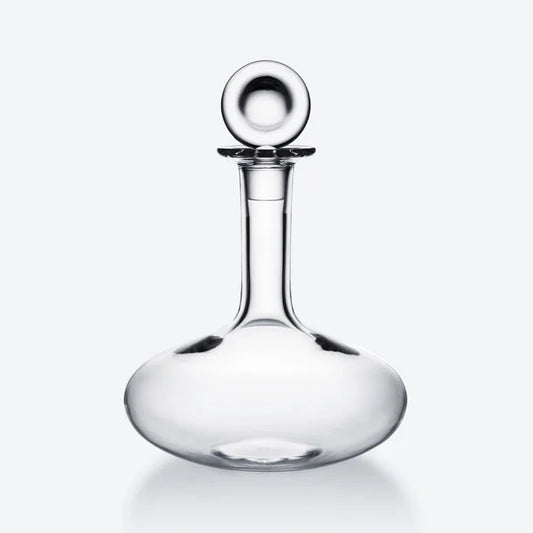 clear crystal wine decanter with a circular lid against a white background