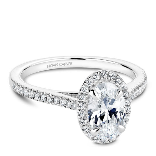 Noam Carver platinum engagement ring with an oval diamond, diamond halo, and smaller diamonds down the sides of the ring against a white background