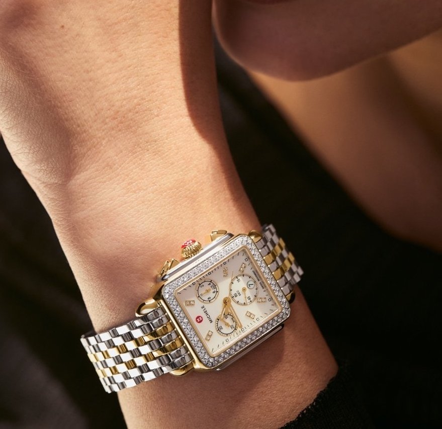 Womans wrist wearing a Michelle watch in rectangle style with diamonds around the face of the watch