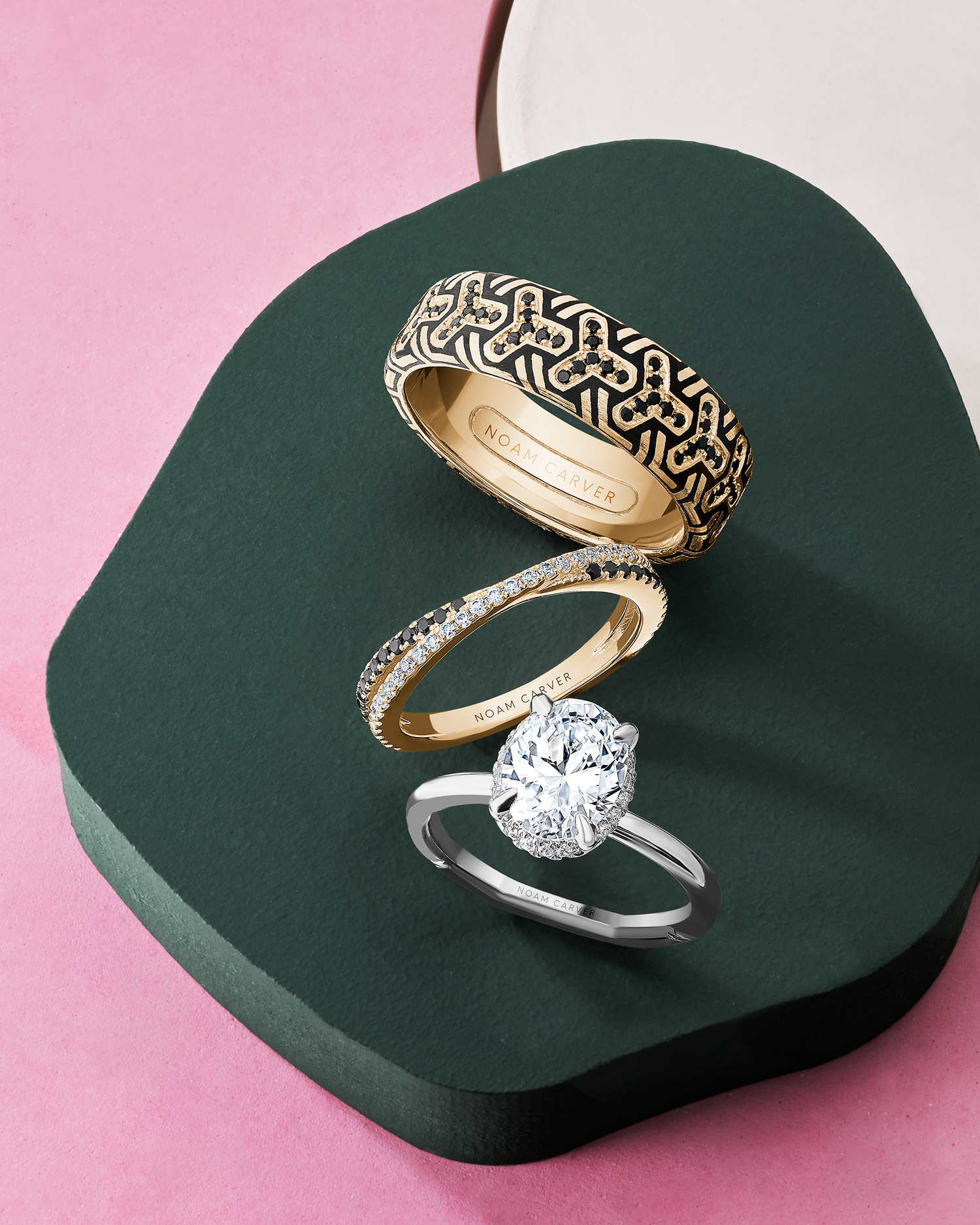 Three men's wedding bands by Noam Carver, positioned on top of gray rocks