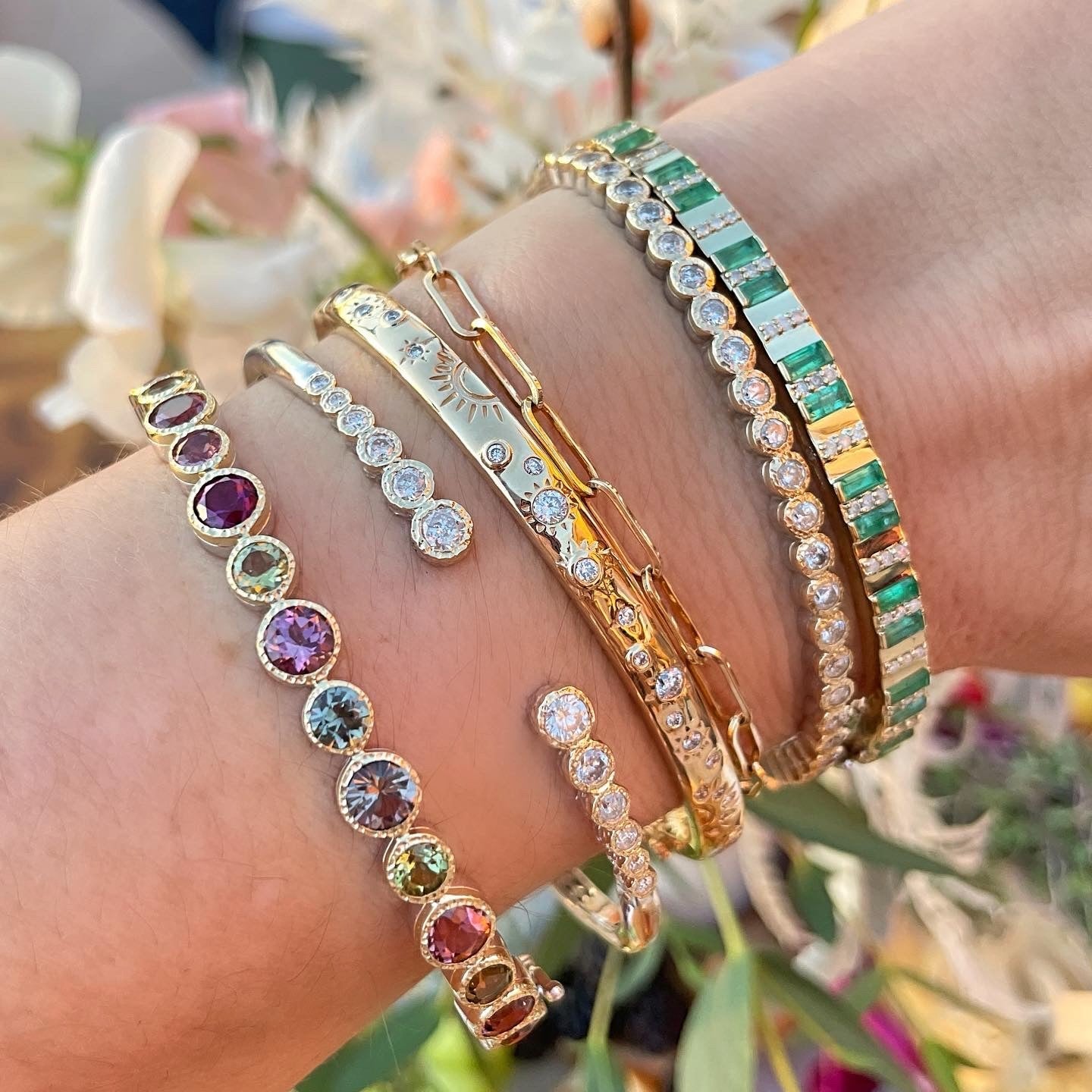 Woman's wrist adorned with six Three Stories bracelets in gold with various diamonds and stones