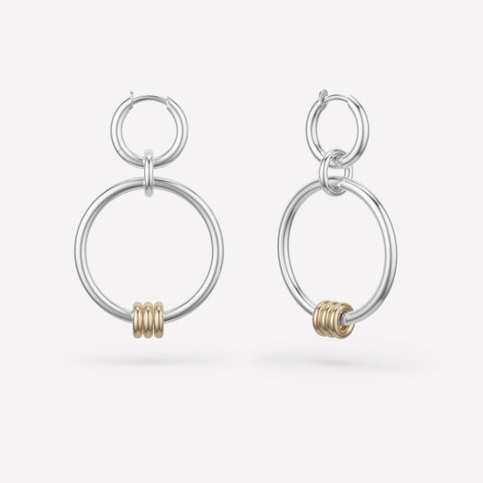 white gold dangle earrings with two hoops and small yellow gold round charms against a white background