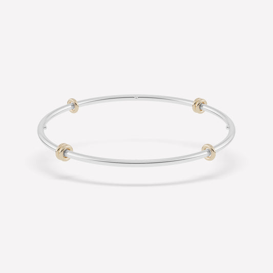 white gold bangle with yellow gold circle charms against a white background