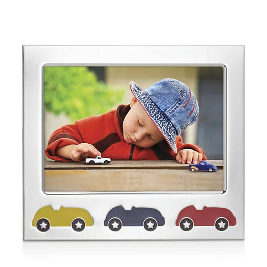 silver-plate picture frame with three racecars in yellow, blue, and red against a white background. center of the frame shows a child in a red sweater and jean hat playing with white and blue racecar toys